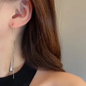 Detailed side view of a minimalist silver water drop tassel ear threader on a model