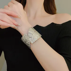 Detailed view of a silver minimalist leaf-textured wide cuff bracelet worn on a wrist