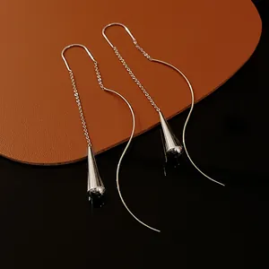 Close-up of minimalist silver teardrop ear line earrings with polished geometric metal pendants.