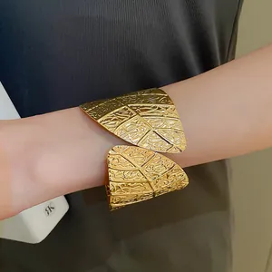 Close-up of elegant gold leaf-patterned cuff bracelet showing metallic texture