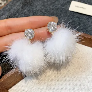 Close-up of elegant silver needle zircon stud earrings with soft white fur balls