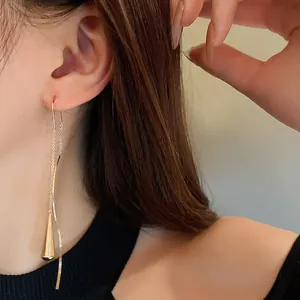 Detailed view of long gold tassel ear line with a metallic teardrop pendant
