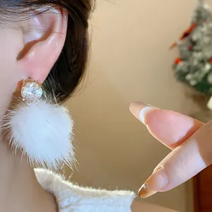 Close-up shot of elegant zircon and white pom-pom earrings perfect for winter outfits