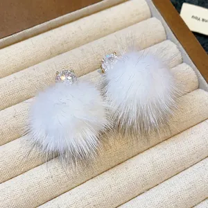 Close-up of elegant S925 silver stud earrings with white pompom and zircon detail.
