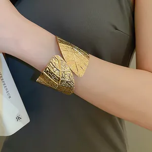 Detailed close-up of wide gold leaf cuff bracelet featuring textured vein engravings