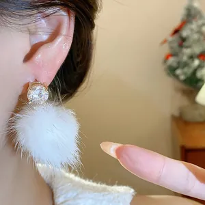 Close-up detail of white fur ball stud earring with sparkling zircon on a model's ear
