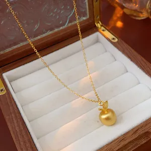 Elegant gold-plated apple pendant necklace with fine chain displayed in a wooden jewelry box