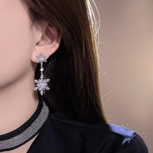 Detailed macro view of shimmering zircon snowflake dangle earring worn by model