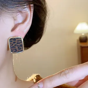 Dettaglio di orecchini a lobo quadrati leopardati vintage con bordo dorato su modella