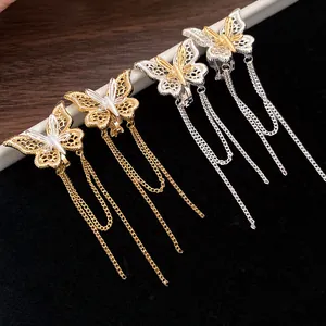 Dettaglio di clip per orecchie a farfalla dorate con eleganti catenelle a nappa.