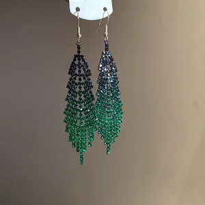Detail view of long fringe earrings with a dark-to-light green rhinestone gradient effect