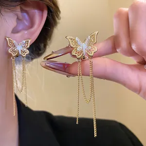 Dettaglio di clip per orecchie a farfalla placcate oro 18k con lunghe catene eleganti.