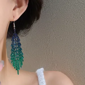 Close-up of blue-to-green gradient rhinestone tassel earring on a model's ear