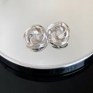 Close-up of silver metal rose knot stud earrings with a high-polished metallic finish.