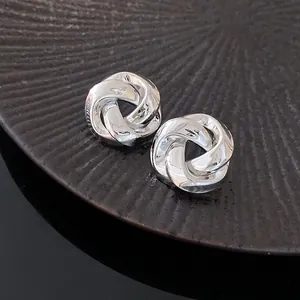 Detailed close-up of French retro silver knotted metal rose stud earrings with glossy finish