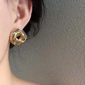 Close-up of gold twisted metal stud earrings with elegant French retro style on ear.