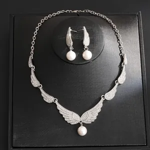 Detailed shot of an elegant angel wing jewelry set featuring rhinestones and white pearls