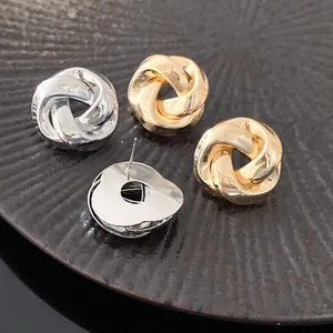 Macro detail of French retro gold and silver twisted knot metal stud earrings on a dark surface