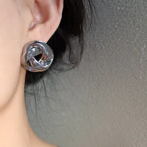Close-up of a silver metal knot stud earring on a model ear, French vintage style.