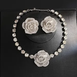 Detailed shot of sparkling rhinestone rose necklace and earring set on black display