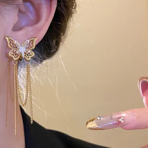 Dettaglio ravvicinato di un orecchino a clip a farfalla placcato oro 18k con eleganti nappe lunghe