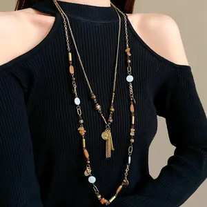 Detailed view of a vintage long layered necklace with a portrait coin pendant and tassels.