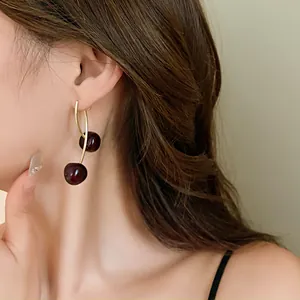 Close-up of a model wearing vintage cherry-shaped resin earrings with elegant gold wires