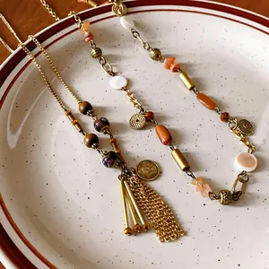 Detail view of retro long sweater necklace with ceramic beads and tassel pendant.