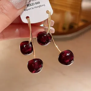 Macro detail view of vintage dark red cherry resin earrings with elegant gold stems.