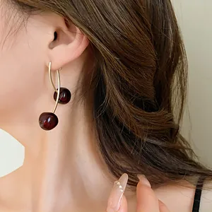 Detailed view of a retro dark red cherry resin earring worn on a female model's ear