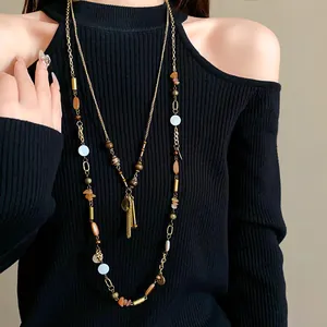 Detailed view of long retro ethnic style necklace with ceramic beads and metallic charms