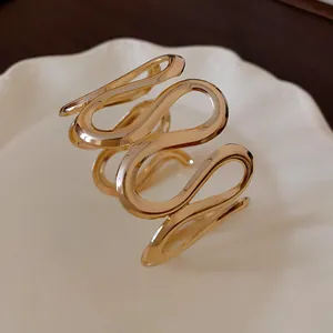 Detailansicht eines goldfarbenen, wellenförmigen Metall-Armreifs mit elegantem Design