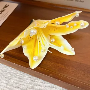 Detail of yellow fabric lily hair clip with delicate white pearl embellishments