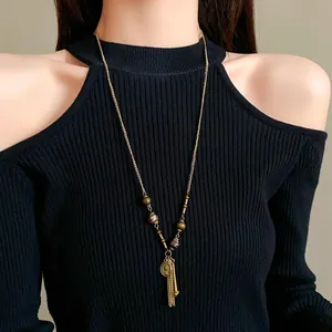 Close-up of vintage long necklace with ceramic beads and portrait coin tassel pendant.