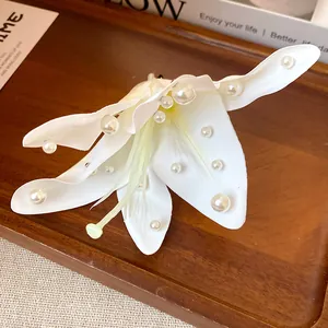 Close-up of white fabric lily hair clip with elegant pearl embellishments on petals.