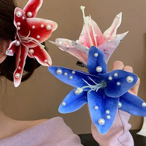 Close-up of fabric lily hair clips with pearl accents in red, pink and blue
