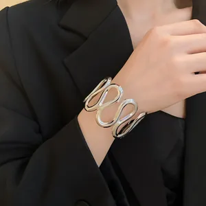 Nahaufnahme eines silbernen, wellenförmigen geometrischen Armreifs am Handgelenk