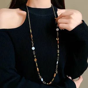 Vintage long necklace with ceramic beads and gold chain worn over black sweater