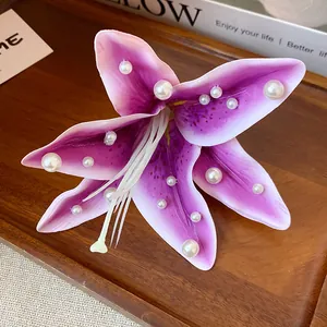 Macro view of a purple fabric lily hair clip embellished with white pearls.