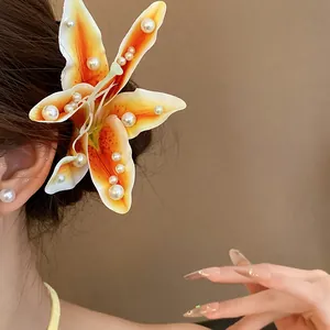 Detailed view of an orange lily fabric hair clip embellished with elegant white pearls