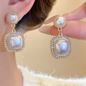 Detailed close-up of elegant square pearl drop earrings with sparkling rhinestone borders