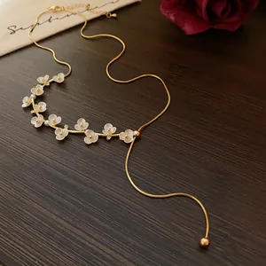 Gros plan d'un collier élégant plaqué or orné de jolies fleurs blanches et de perles