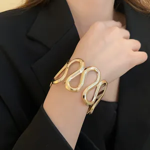Detailansicht eines eleganten, goldfarbenen Metall-Manschettenarmbands am Handgelenk
