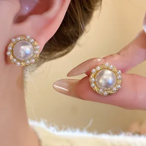 Close-up view of vintage gold-tone earrings featuring a large pearl and pearl border