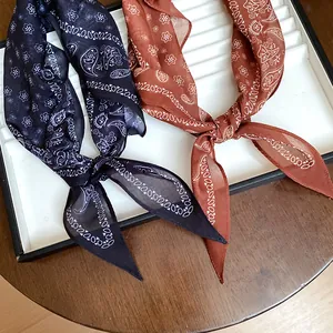 Gros plan de foulards en soie à imprimé cachemire rétro en bleu marine et rouille sur plateau.