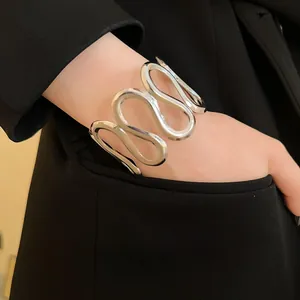 Detailansicht eines silbernen, wellenförmigen Armreifs, kombiniert mit einem schwarzen Blazer.