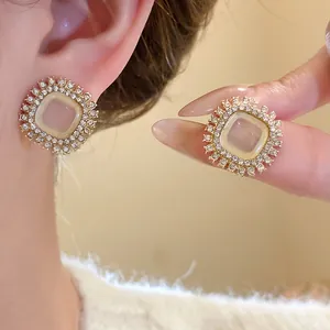 Detail of vintage square earrings with sparkling rhinestones and an opalescent center stone