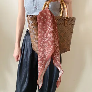 Foulard en soie vintage imprimé paisley noué sur un sac en bambou tressé avec poignée