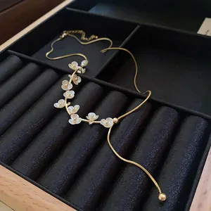 Gros plan détaillé d'un collier plaqué or avec des motifs de fleurs blanches et cristaux