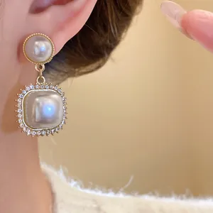 Detailed close-up of vintage geometric pearl earrings with shimmering rhinestone borders